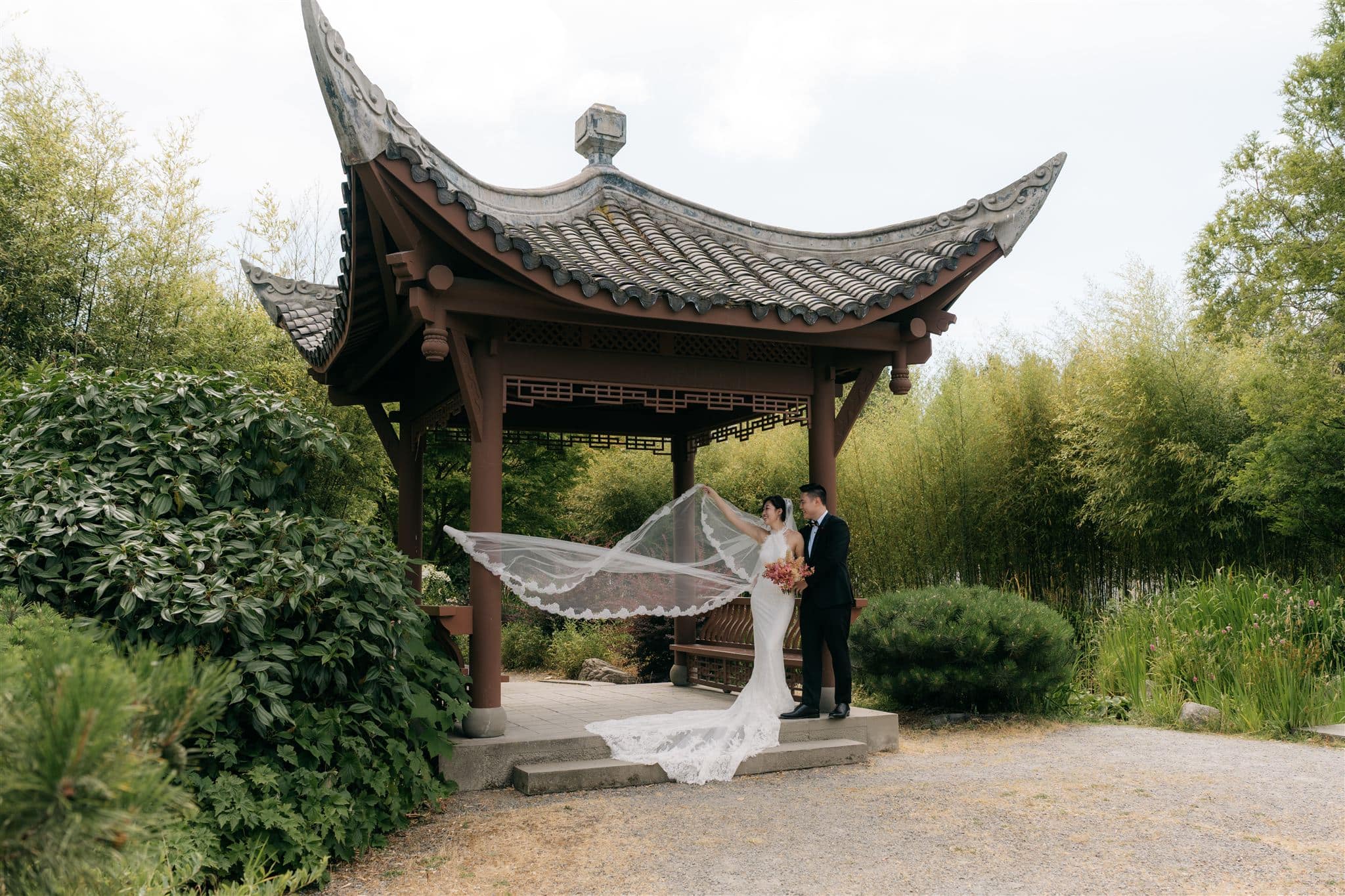Bride and groom stand under a pergola at Seattle Chinese Garden wedding venue.