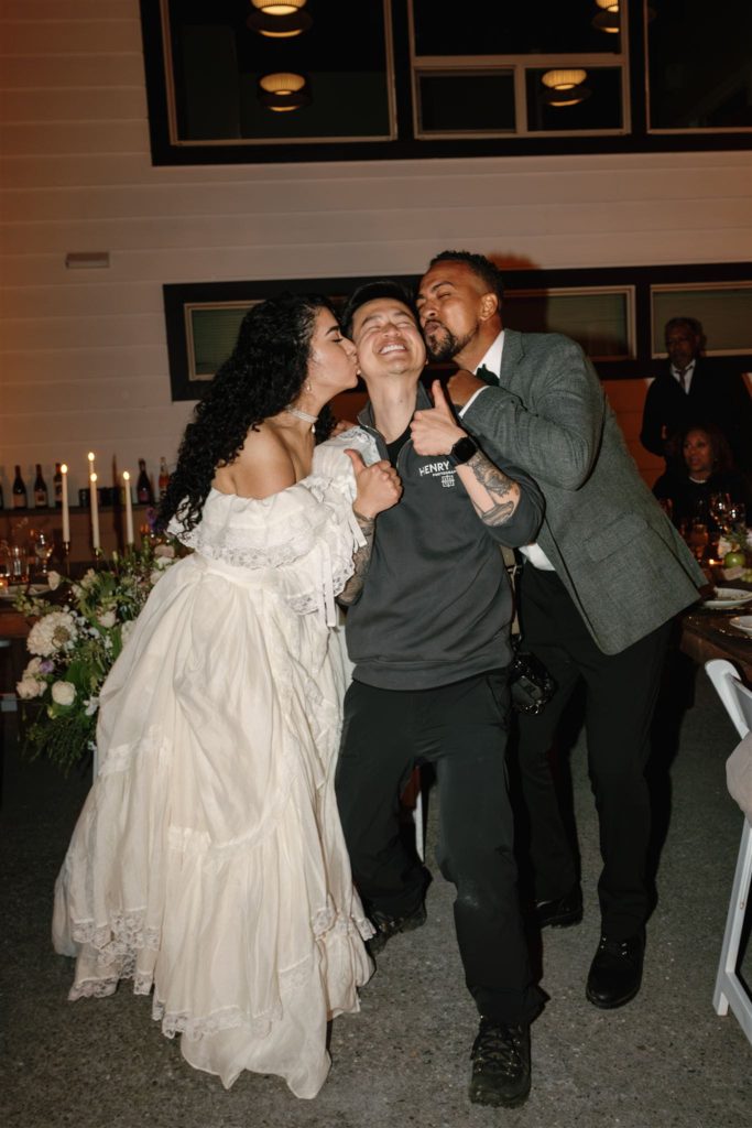 Bride and groom kiss Oregon elopement photographer on the cheek at the end of their Sandstone Point wedding.
