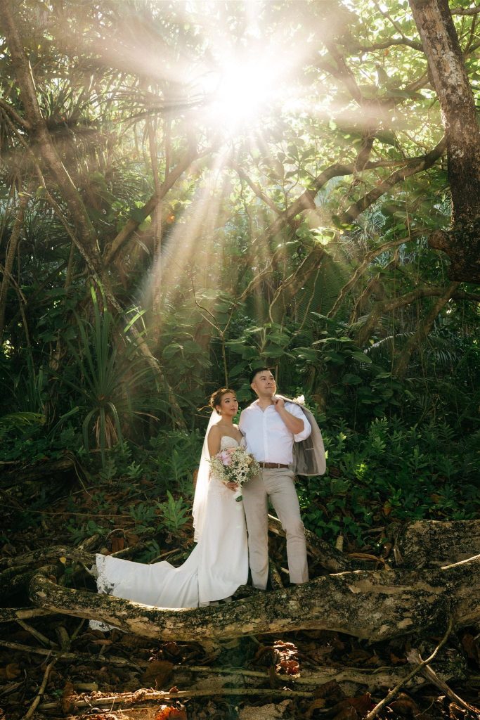 Kauai elopement photos in the forest with filtered sunlight above the bride and groom.