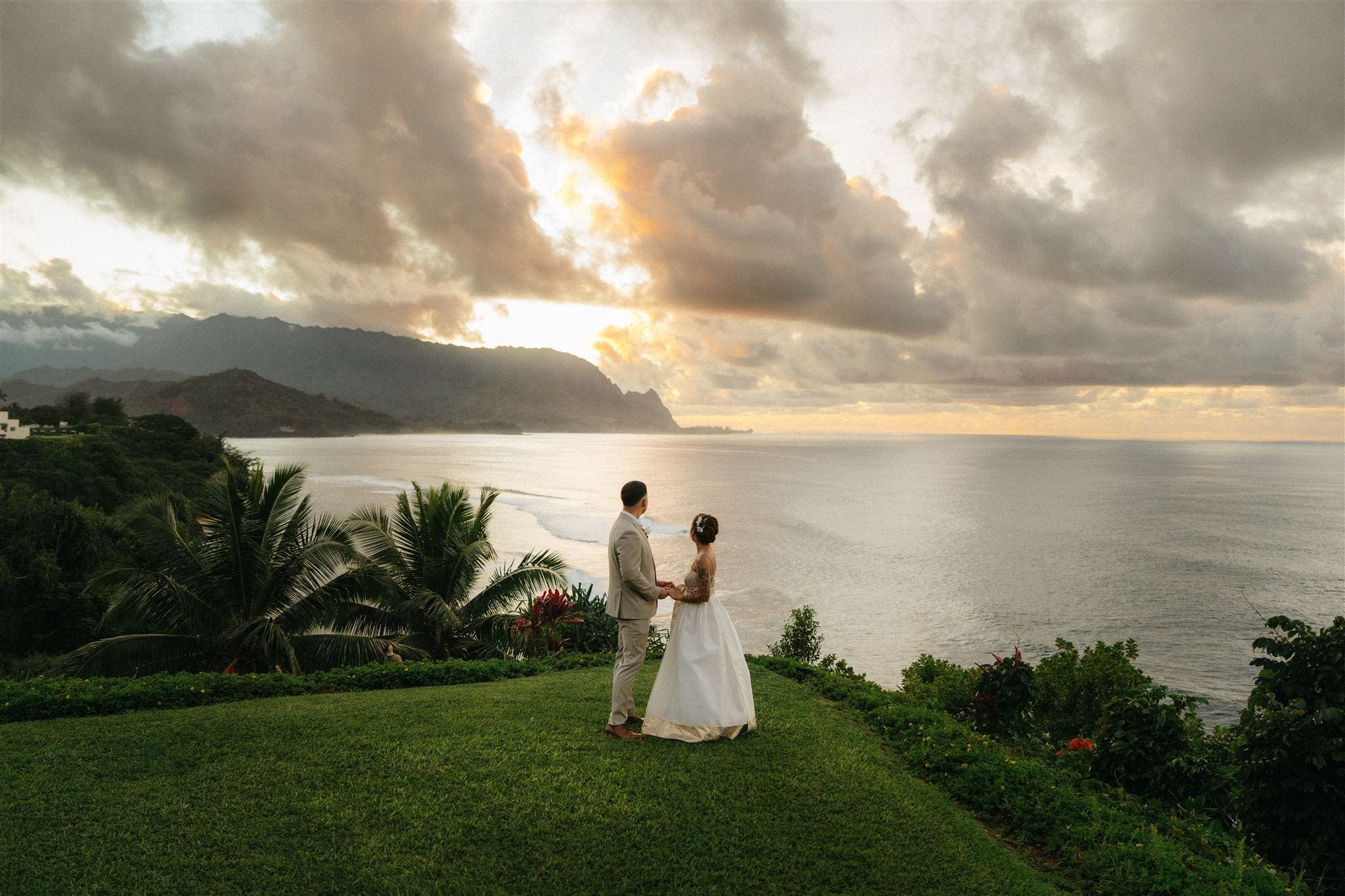 Newlyweds in hanbok outfits watch a Kauai sunset during their two-day luxury elopement.