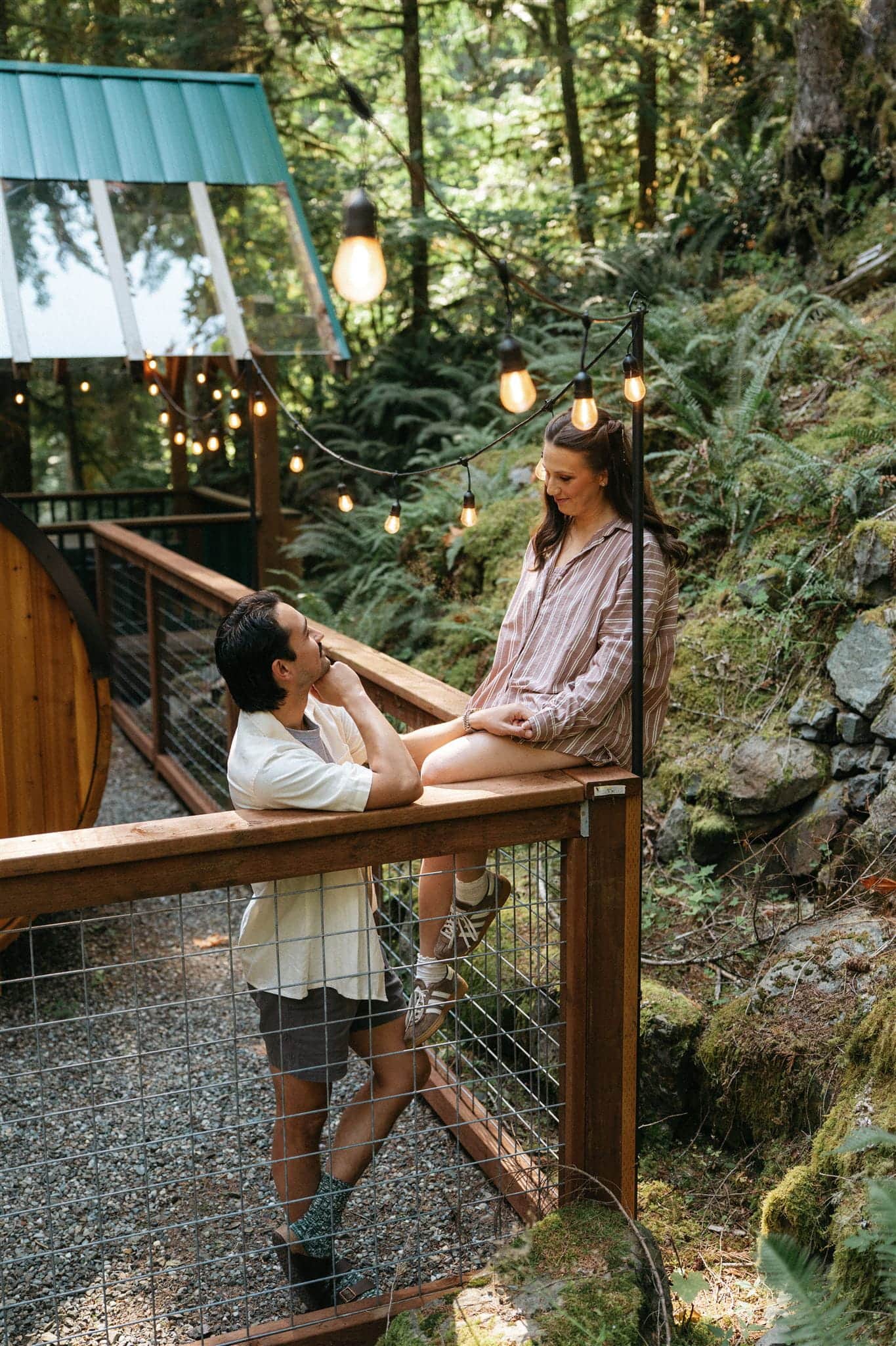 Couple lounges on an outdoor patio with string lights before getting ready for their Mount Baker elopement.