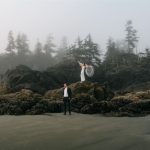 Newlyweds stand on a rock formation during their Tofino beach elopement.