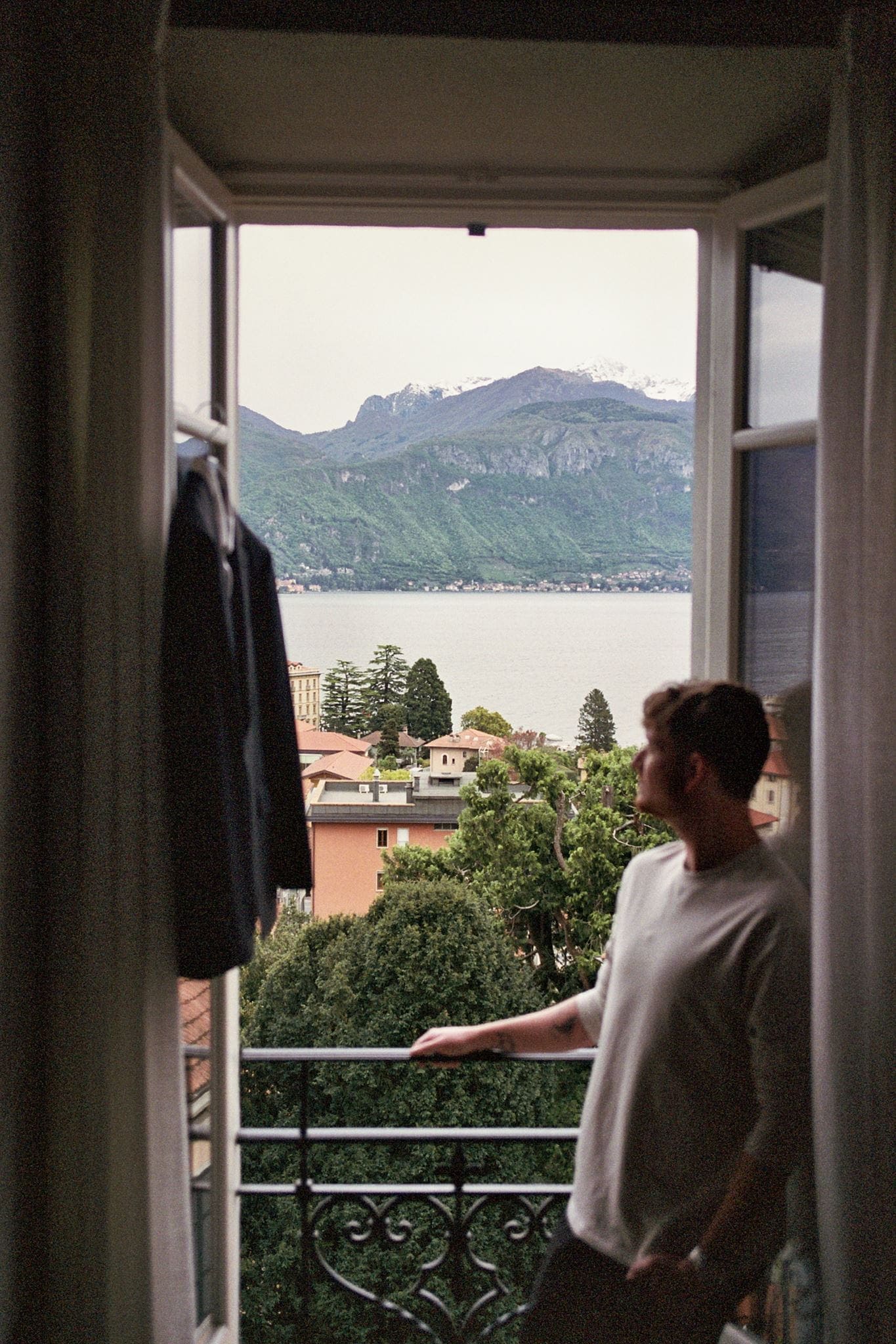 Groom leans against a doorjamb before getting ready for his elopement in Lake Como. Shot on film.