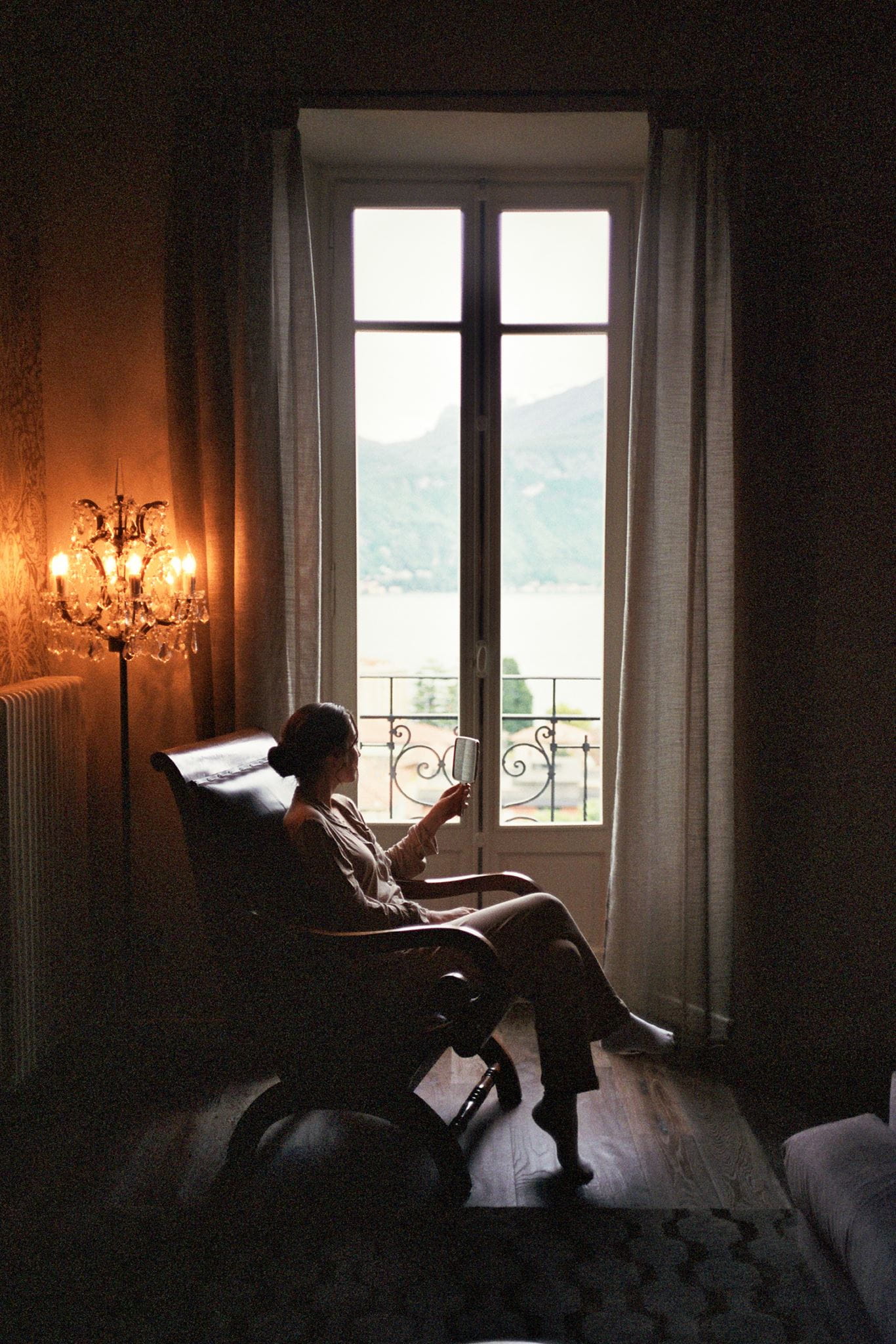 Bride sits in a chair reading before getting ready for her elopement in Italy. Shot on film.