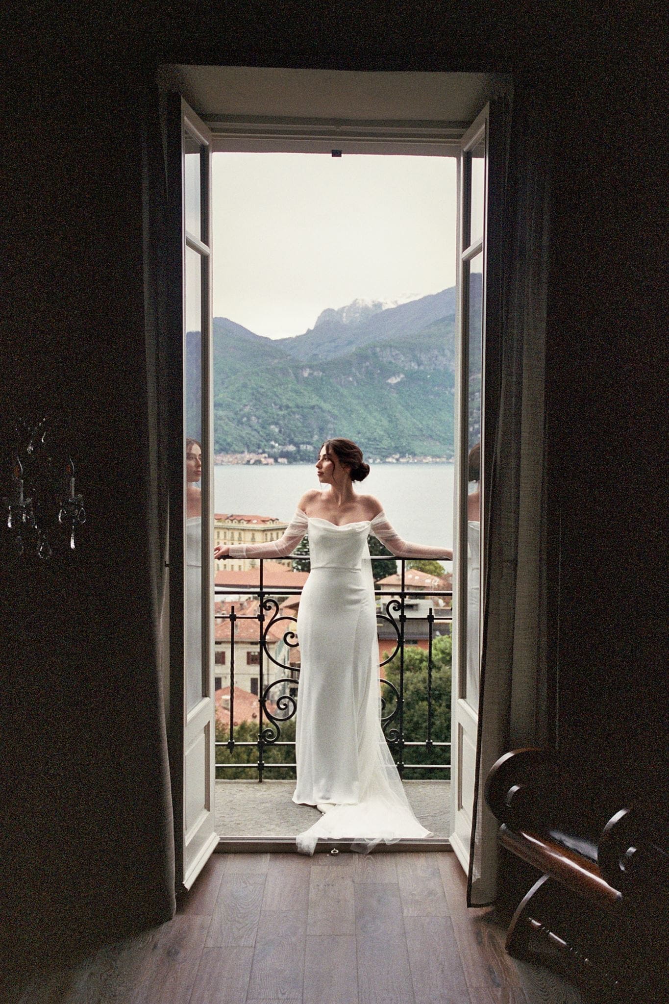 Film photo of bride leans against a railing overlooking Lake Como after getting ready for her elopement.