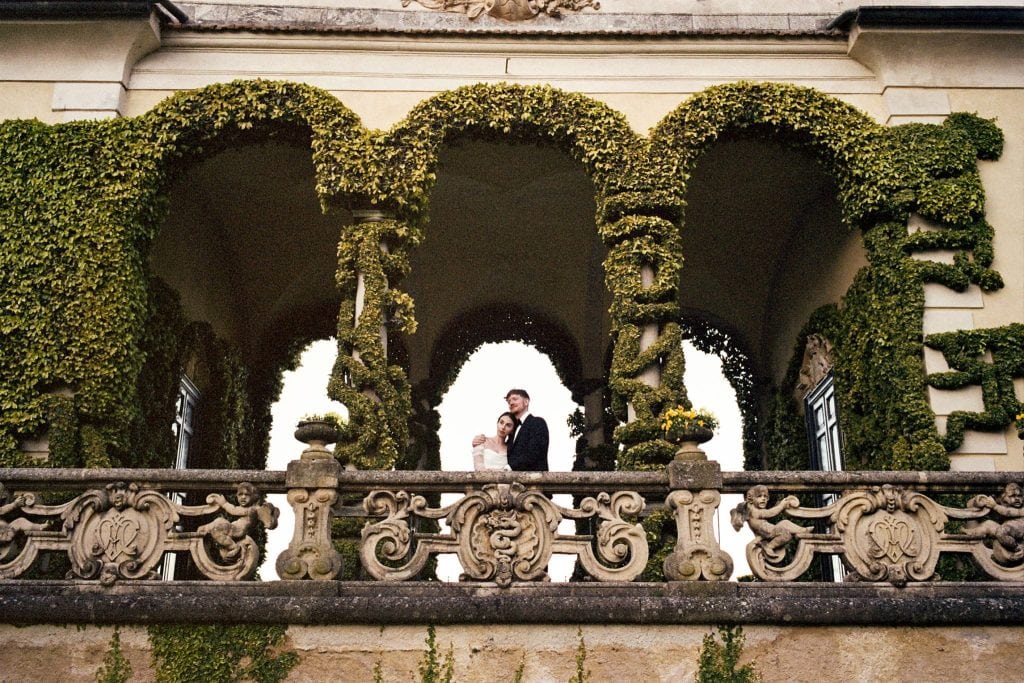 Newlyweds stand under archway during their elopement film wedding photos in Lake Como, Italy.