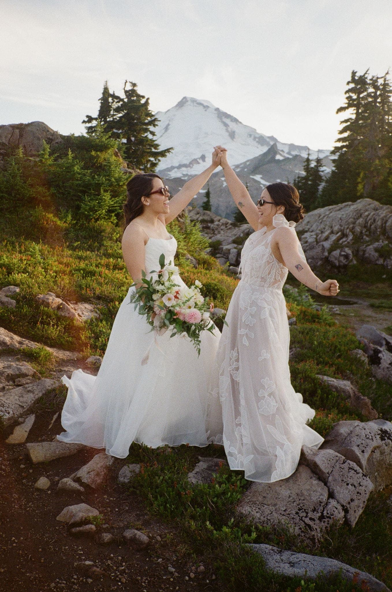 Brides dance on a mountain trail at Mt Rainier National Park during their film elopement photos.