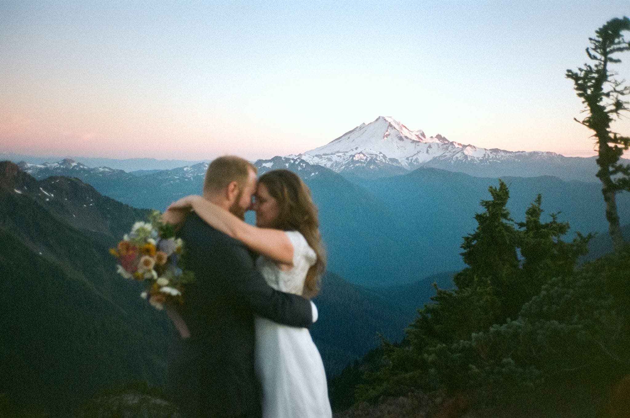 Bride and groom slow dance in the North Cascades during their film wedding photos at sunset.