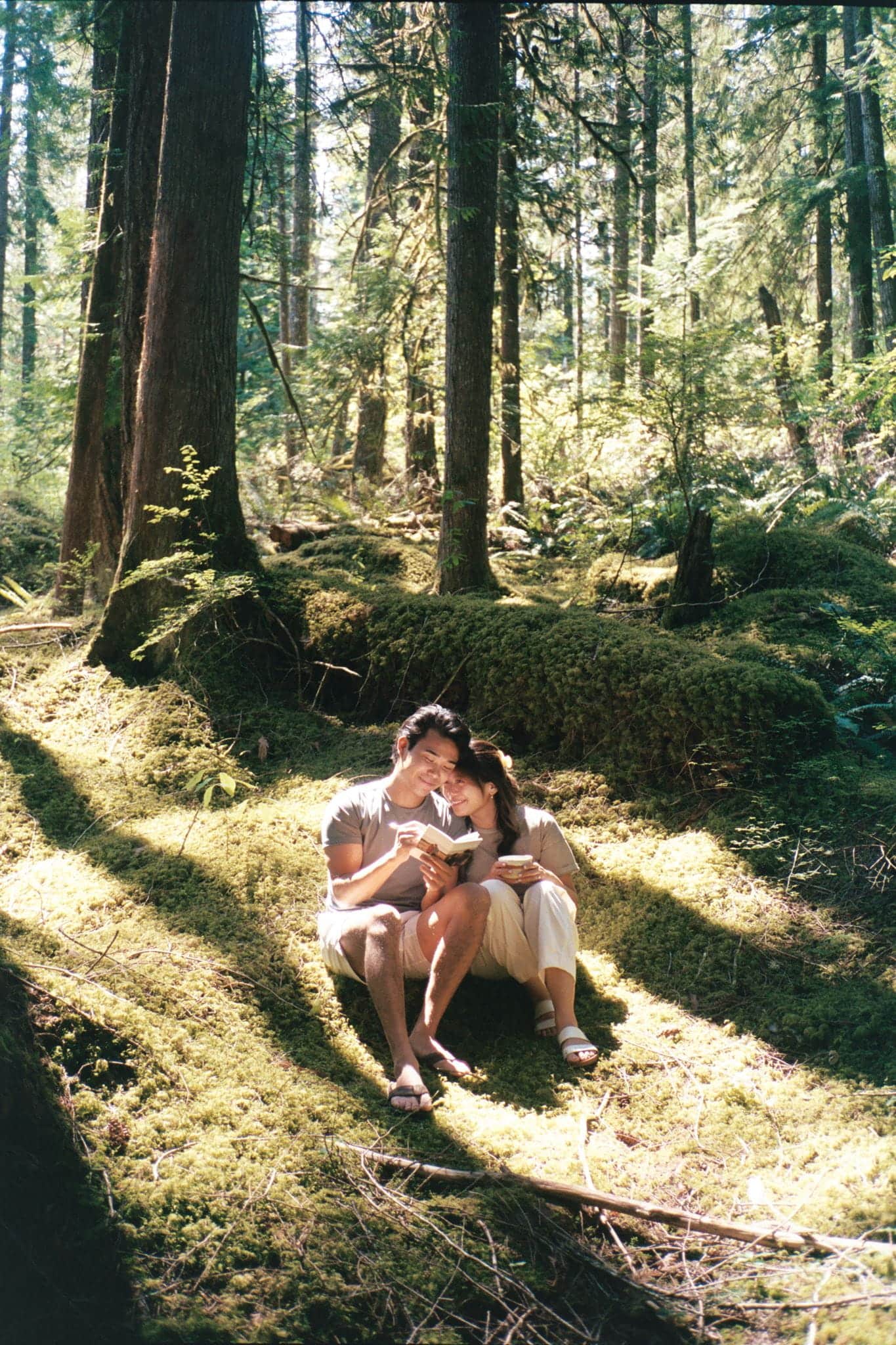 Couple sits on a mossy forest floor in Washington reading letters. Shot on film.
