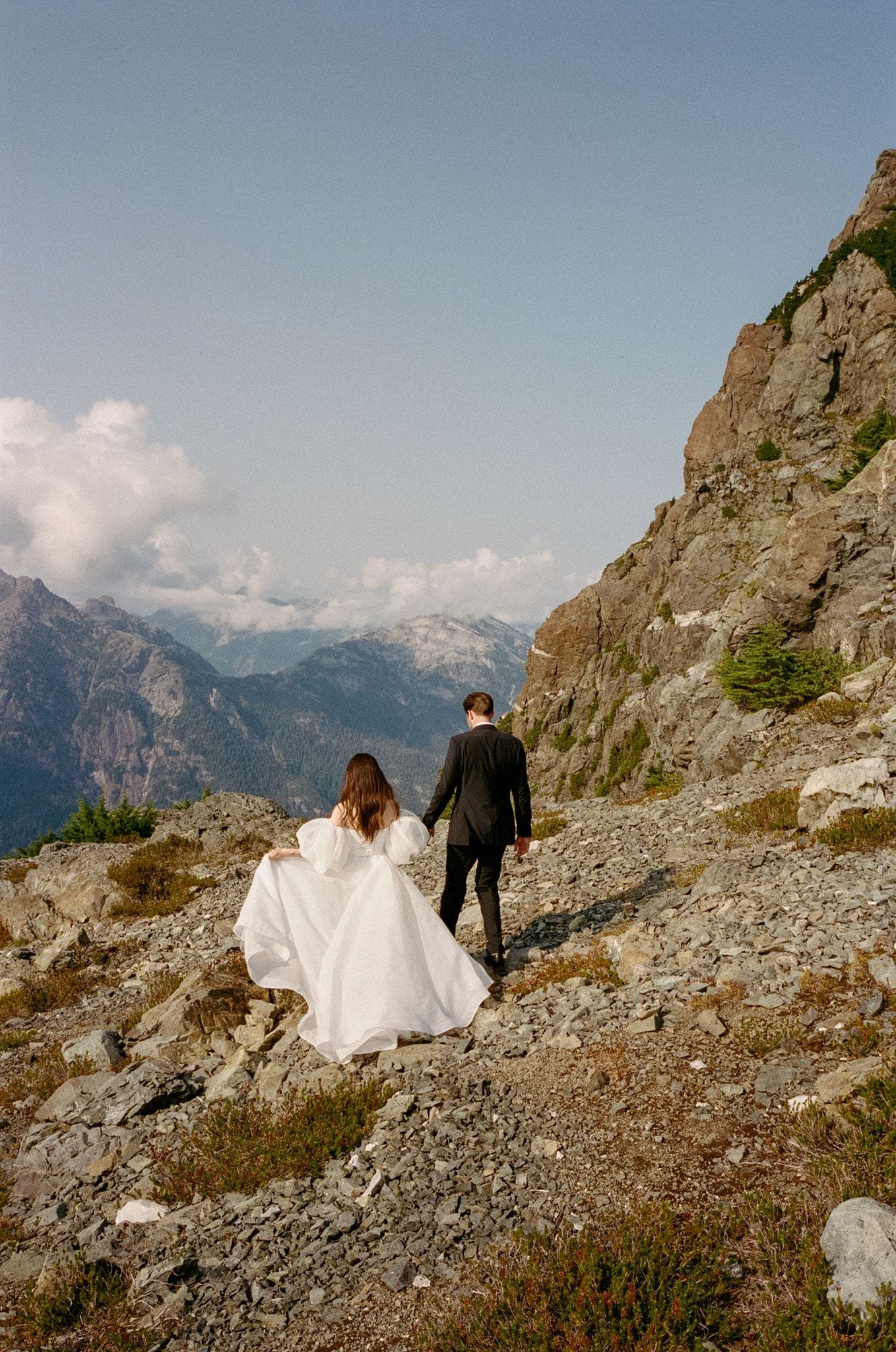 Bride and groom walk along a mountain trail in Tofino, British Columbia.