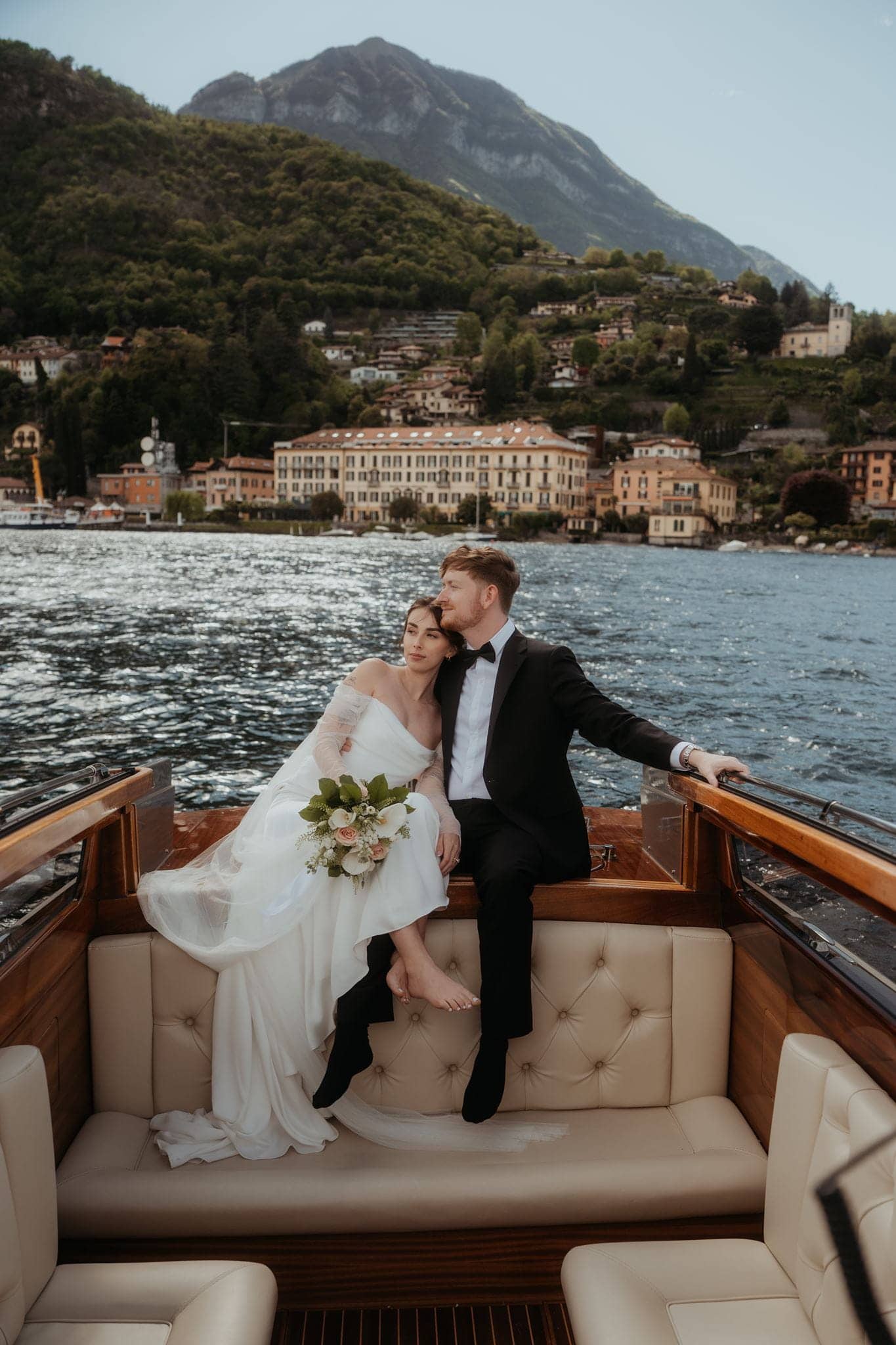 Bride and groom ride on the back of a boat around Lake Como in Italy.