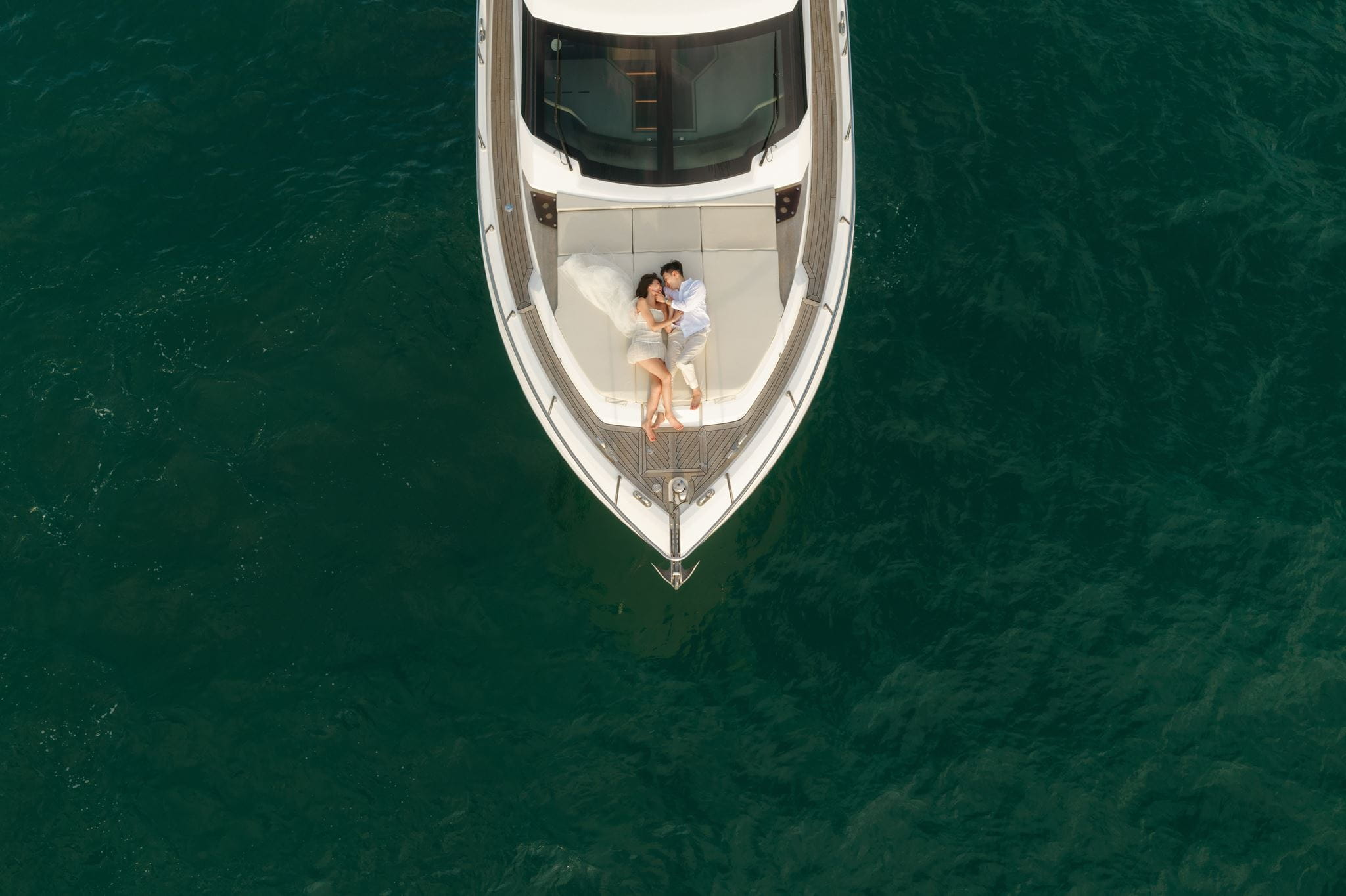 Couple lays on a boat deck during their Vietnam engagement photos.