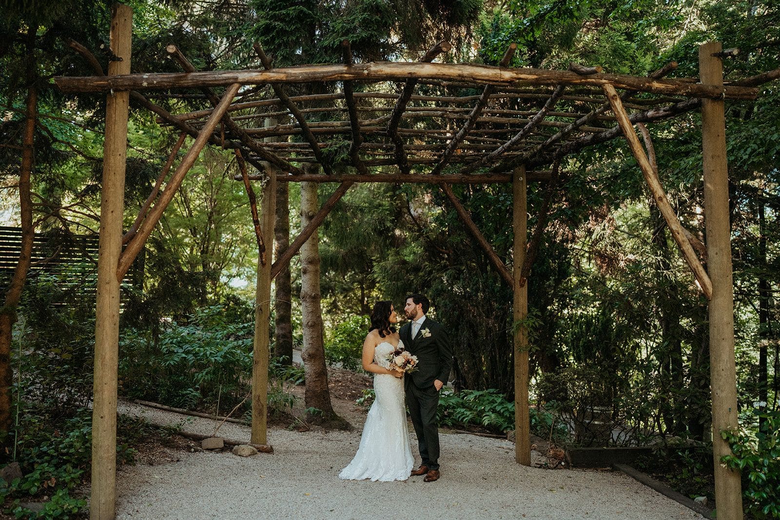 Newlyweds stand under a wood pavilion at JM Cellars in Washington.
