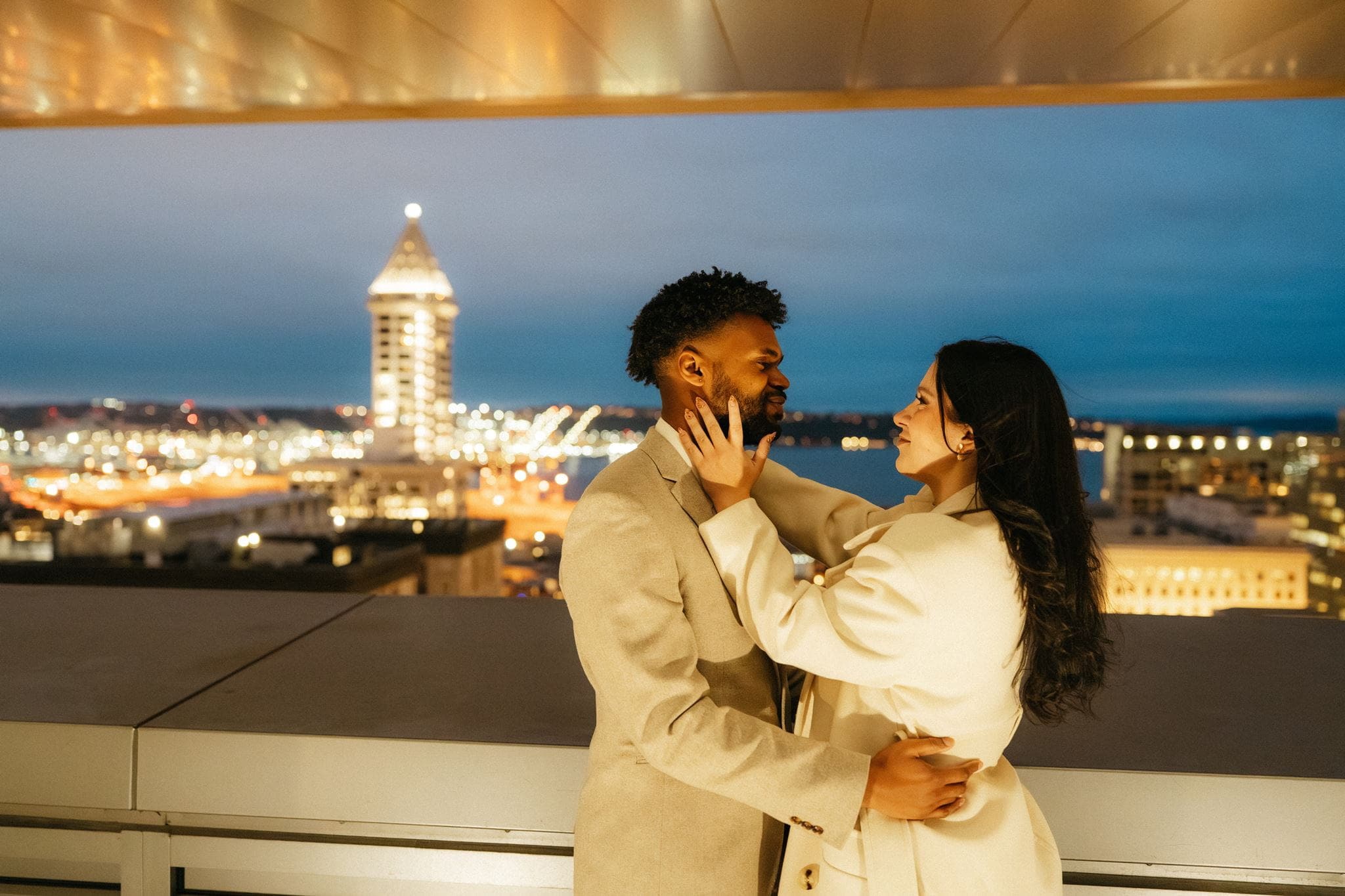 Newlyweds hug on a rooftop overlooking Smith Tower during their Seattle courthouse wedding.