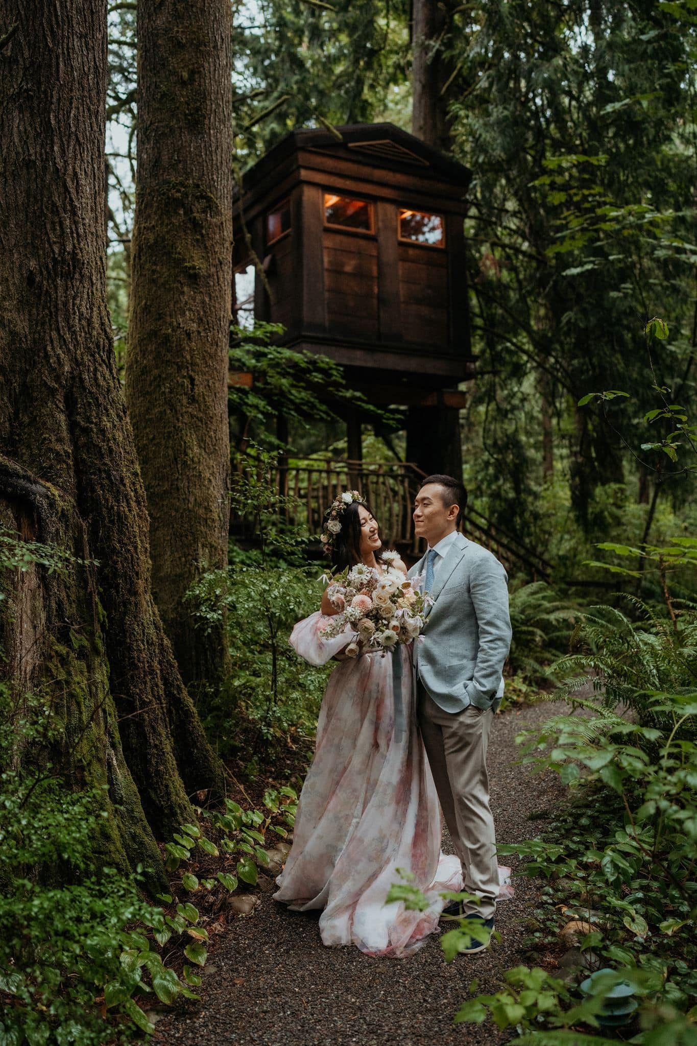 Newlyweds stroll through the forest at Treehouse Point, a micro wedding venue in Washington.