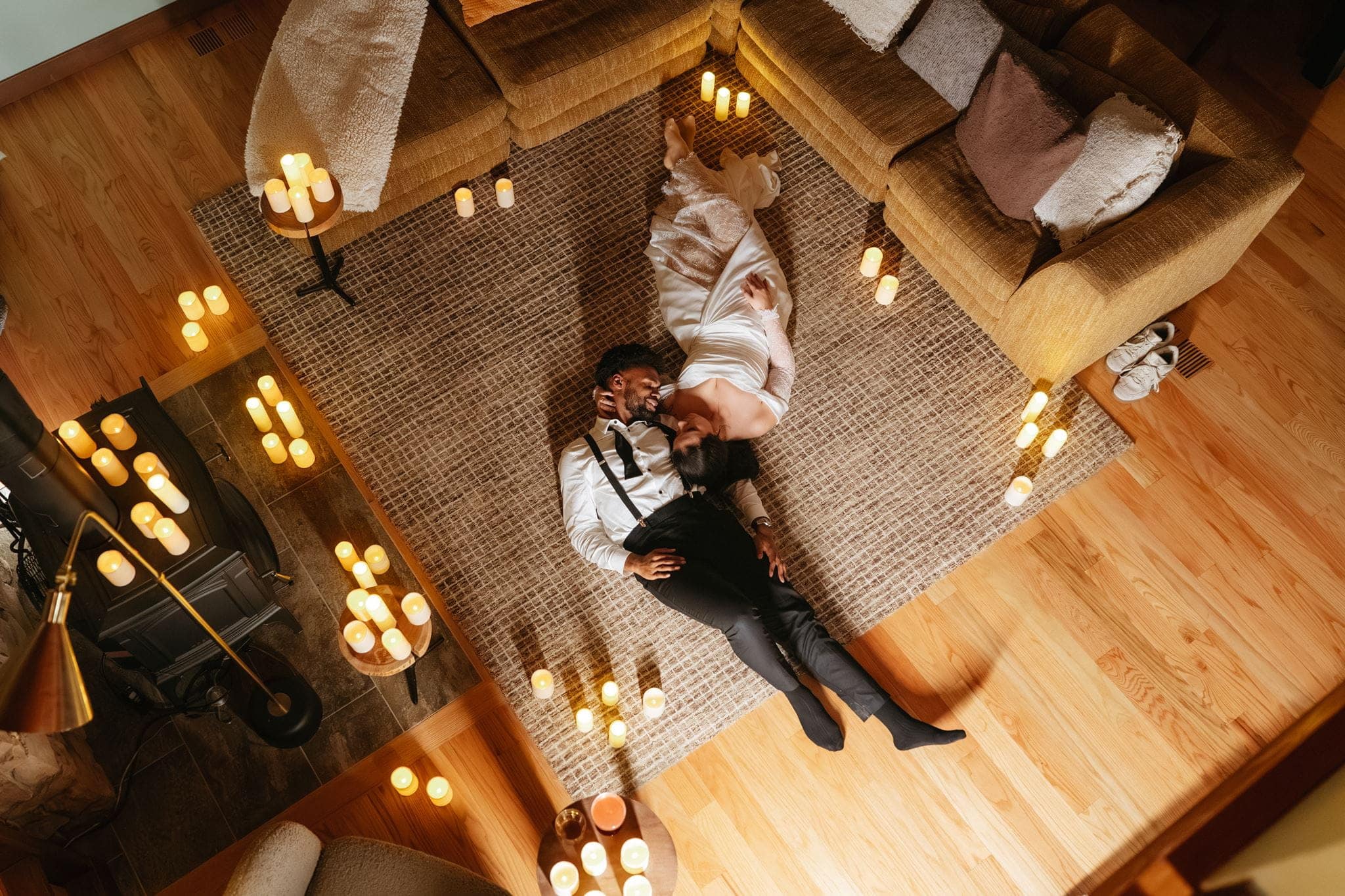 Bride and groom lay on the ground of their cabin surrounded by candles.
