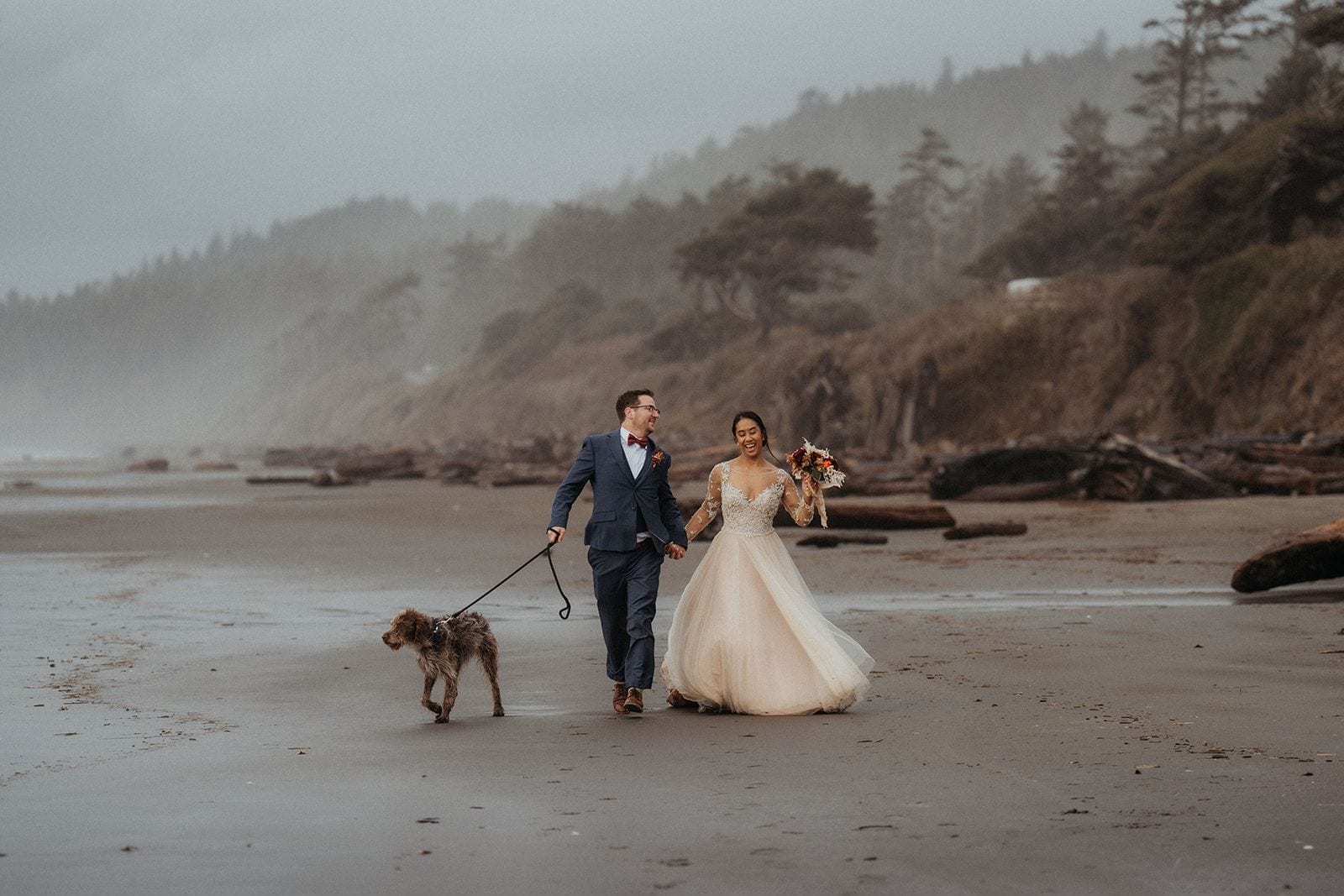 Newlyweds run across the beach with their dog on the Olympic Coast.