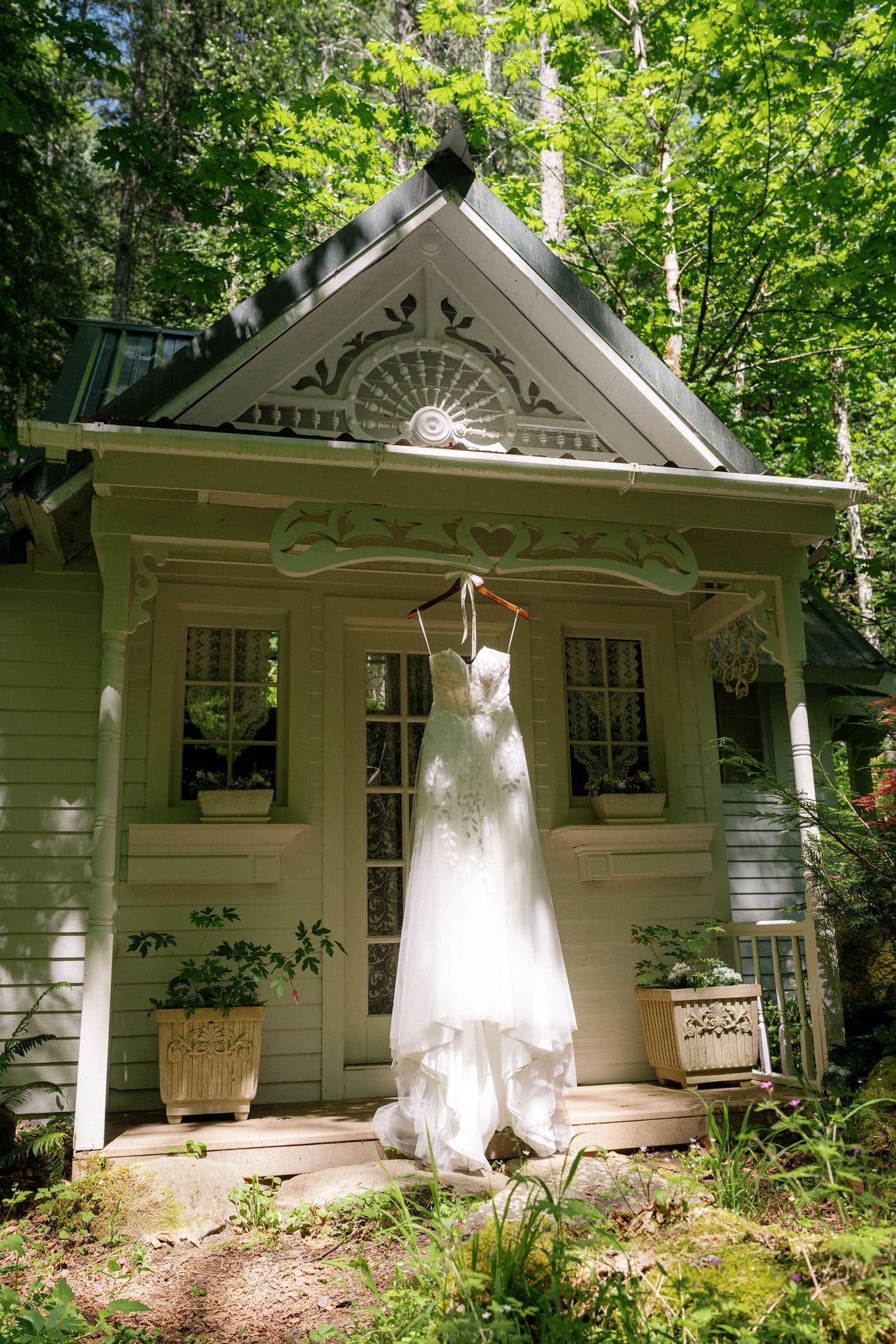 White wedding dress hangs from the roof of a white cabin at Wellspring Spa, a micro wedding venue in Washington State.
