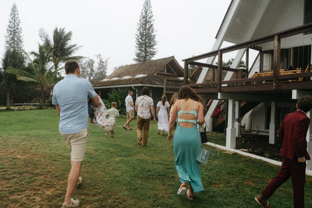 Guests head back into their Hawaii Airbnb during a tropical rainstorm at a micro wedding ceremony.