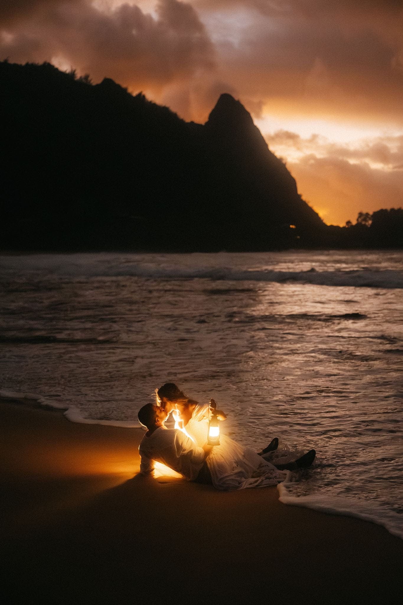 Newlyweds kiss on a beach after sunset during their Hawaii micro wedding.